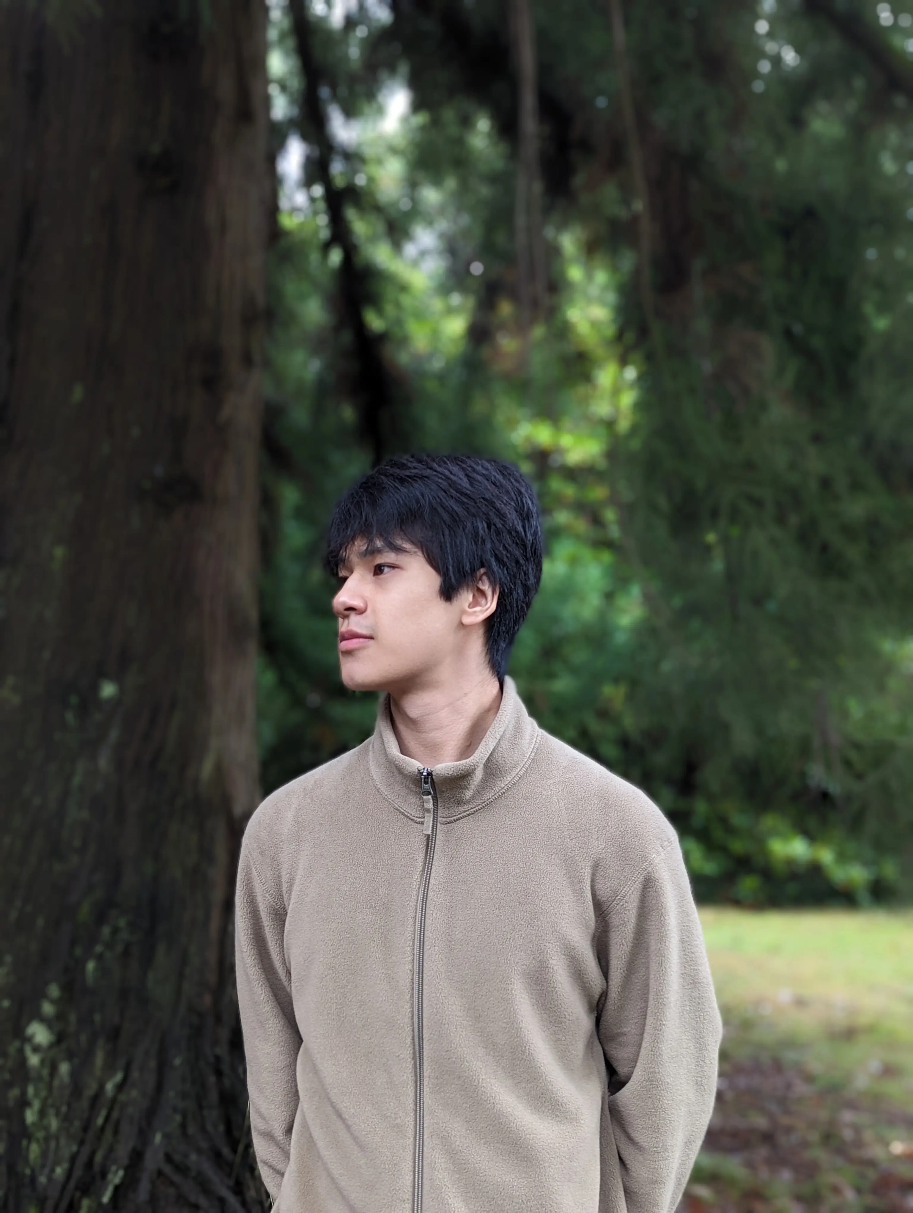 portrait image of Huy standing in front of a tree and foliage